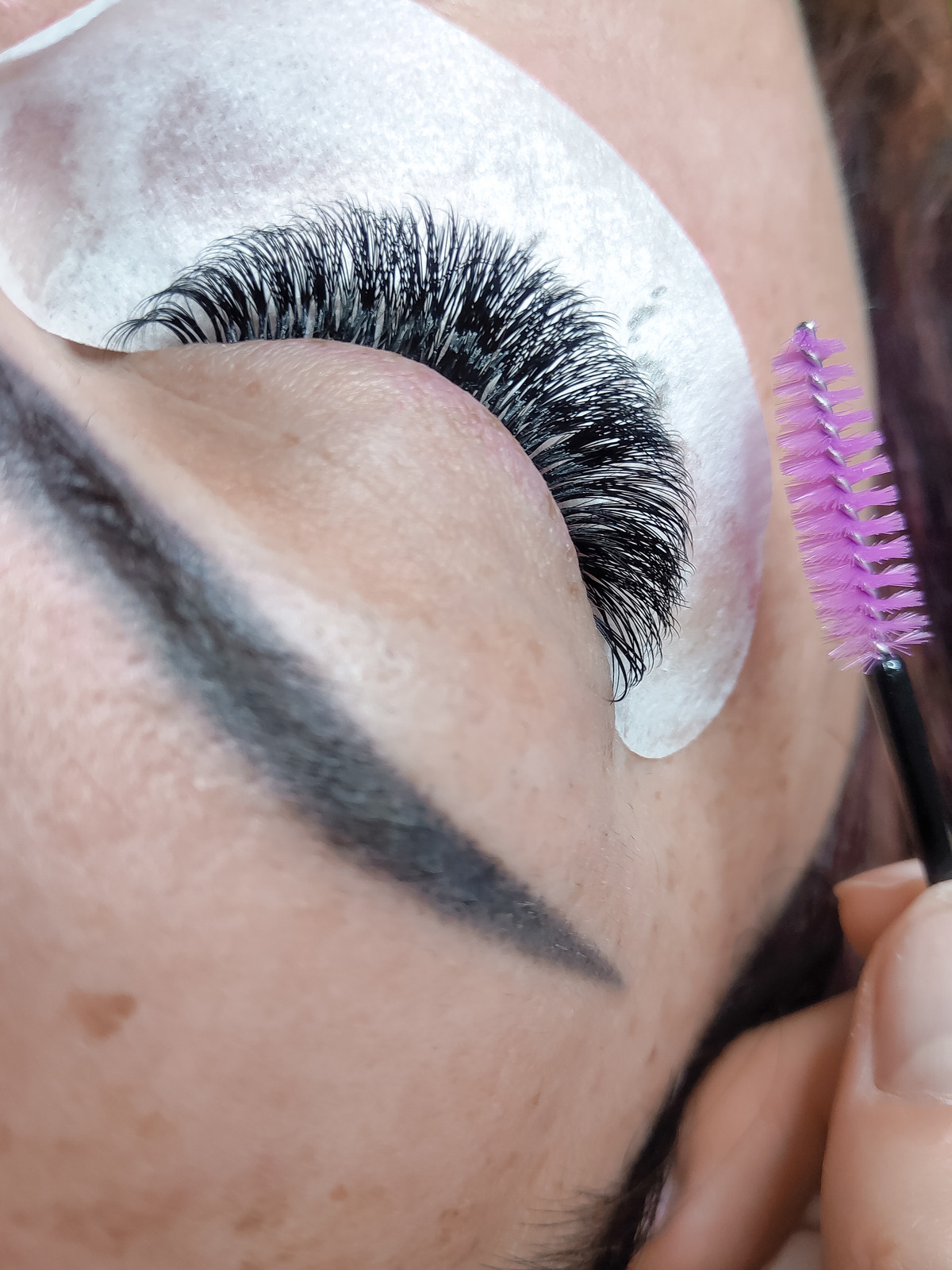 Brushing through freshly applied lash extensions