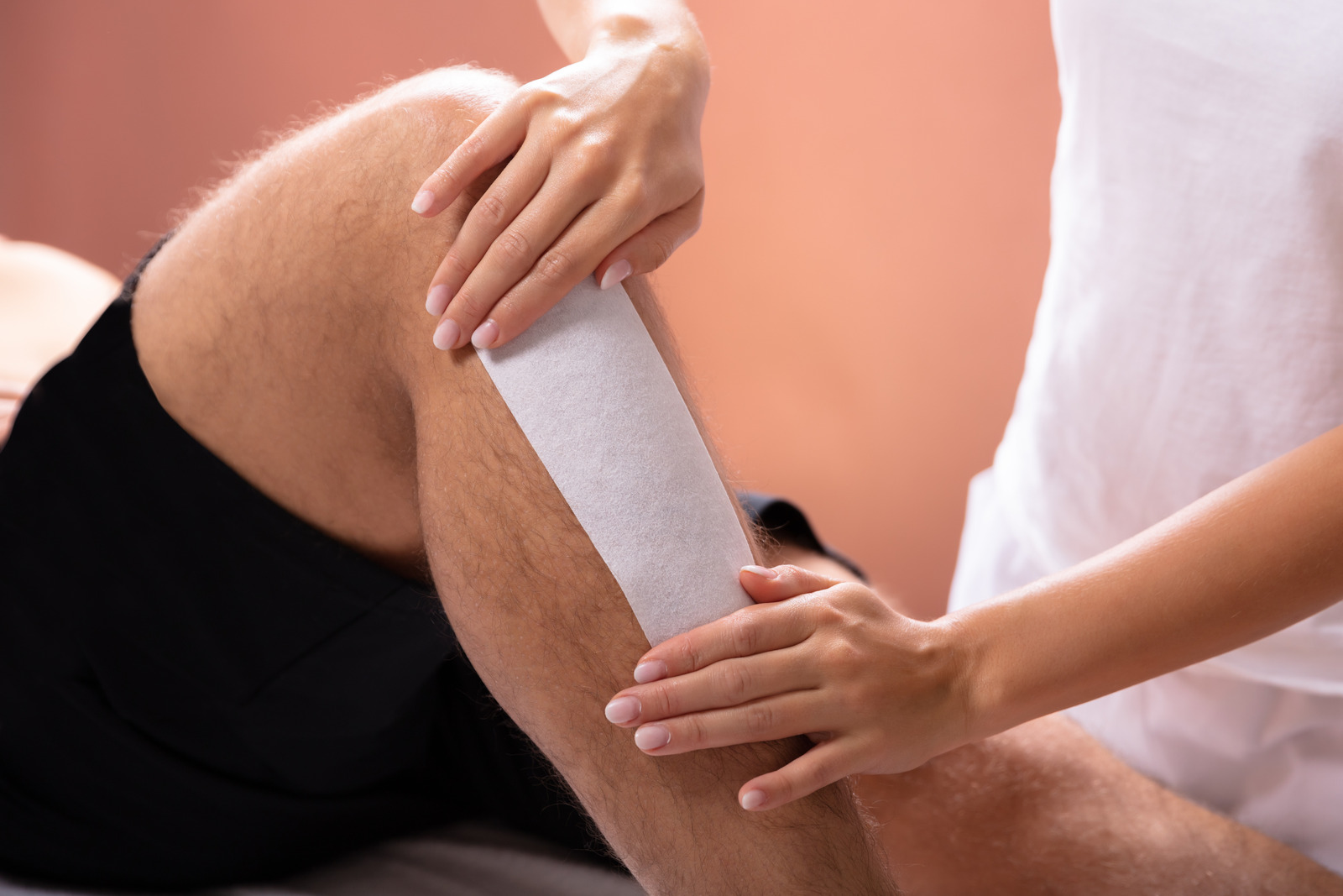 Applying wax strip to the leg